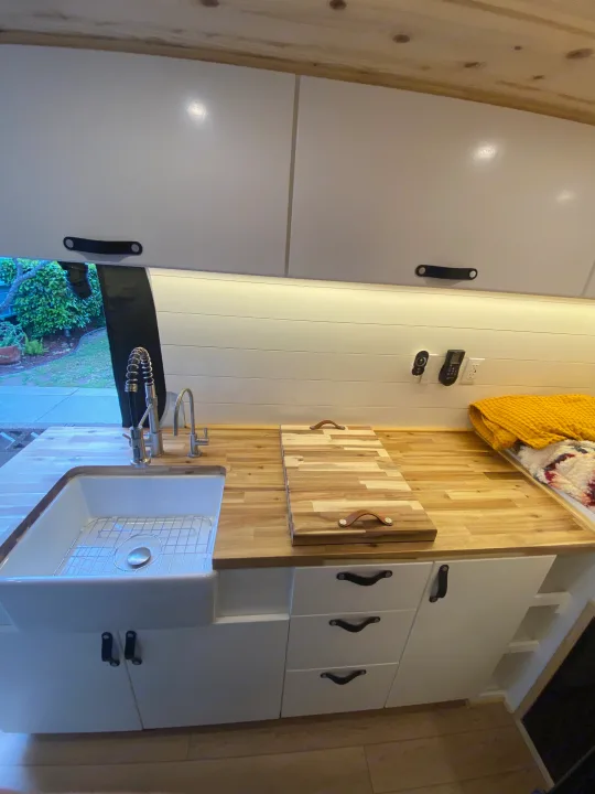 RV rental interior: A bright, modern kitchen features a large white sink, butcher block counters, and ample white cabinetry.. Mercedes-Benz Sprinter 2022