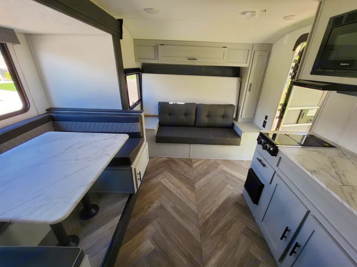RV rental interior: A compact living area with a dinette, convertible sofa/bed, and kitchen. Ready for your next adventure.. Forest River Wildwood FSX 2021