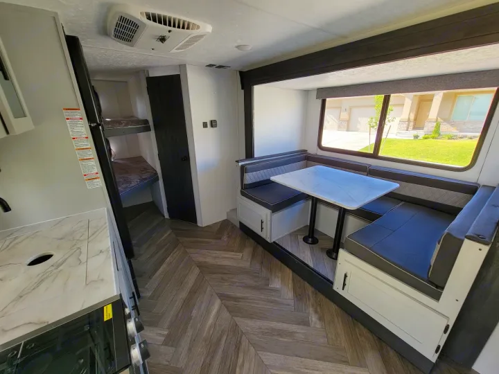 Spacious RV rental interior with a comfortable dinette, kitchen area, and visible bunk beds. Perfect for family adventures.. Forest River Wildwood FSX 2021