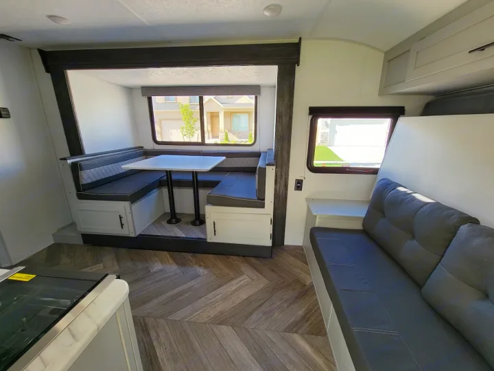 Inside a clean RV rental featuring a U-shaped dinette with a table and comfortable sofa seating.. Forest River Wildwood FSX 2021