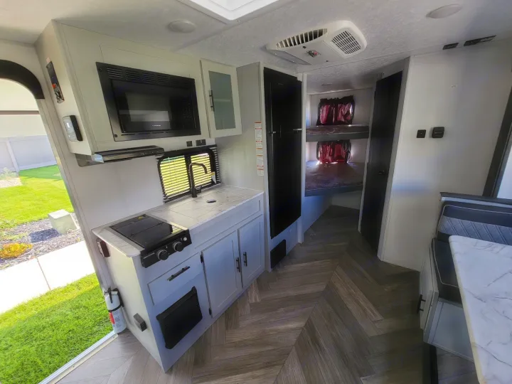 Modern RV rental interior with kitchen, fridge, bunk beds & dining space. Ideal travel trailer for family trips.. Forest River Wildwood FSX 2021