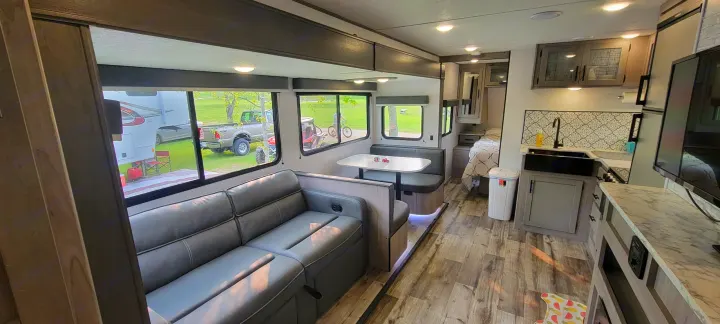 Explore this modern RV rental interior: spacious living area with sofa, dinette, full kitchen, and cozy bedroom. Ideal for trips!. Dutchmen Coleman Light 2022