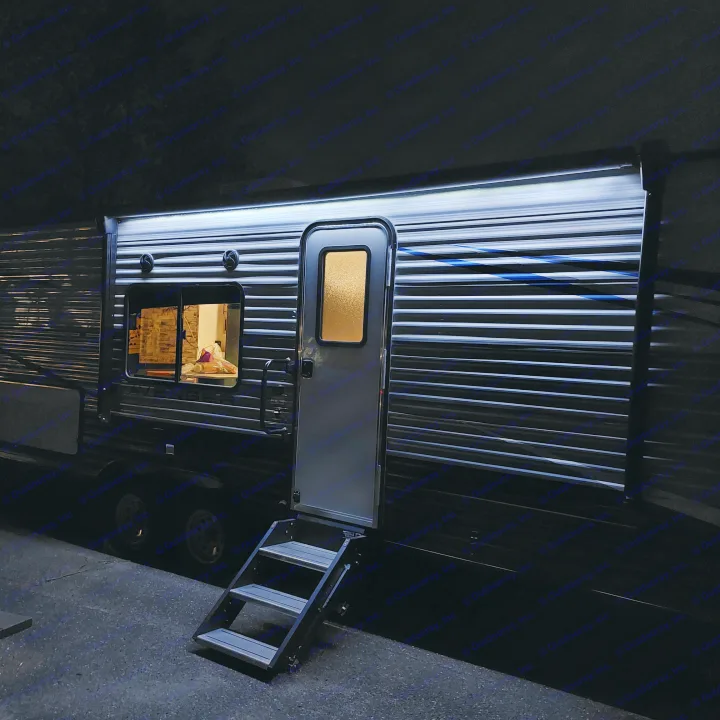Dark shot of an RV rental's ribbed side with open door, extended ladder. Glimpse inside shows light & interior details.. Avenger Avenger Trailer 2021