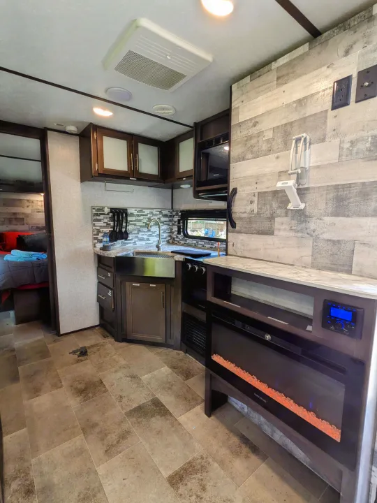 Experience comfort in this modern RV rental: a well-appointed kitchen, electric fireplace, and cozy bedroom area.. Coleman Lantern 2021