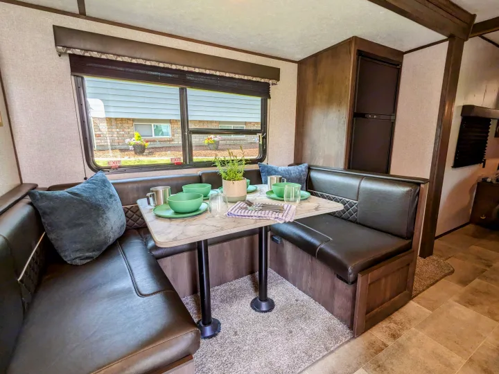 Enjoy a cozy RV rental experience! This dinette features comfortable booth seating, a compact table, and a view outside.. Coleman Lantern 2021