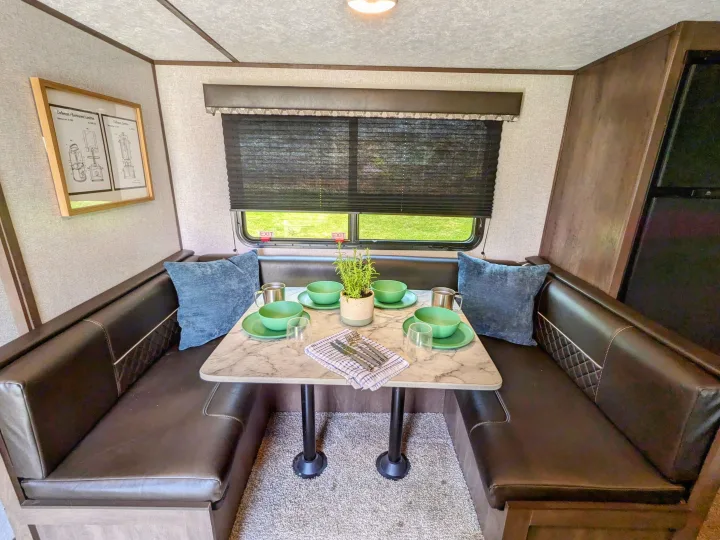 Cozy RV rental dinette setup, complete with green dishes, comfortable seating, and lantern artwork. Perfect for travel!. Coleman Lantern 2021