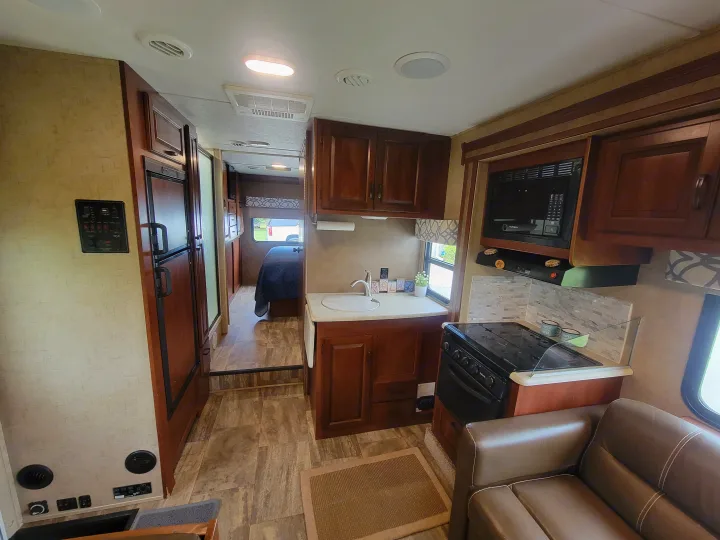 This inviting RV rental interior showcases a full kitchen, living space, and a cozy bedroom, ideal for mobile adventures.. Forest River Sunseeker 2017