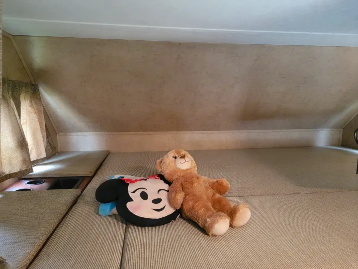 Inside a cozy RV rental: an overhead bunk bed with a Minnie Mouse pillow and teddy bear, ready for restful sleep.. Forest River Sunseeker 2017