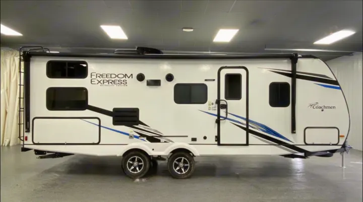 White Coachmen Freedom Express travel trailer RV with black/blue accents, seen indoors. Great for an rv rental.. Coachmen 257BHS 2022