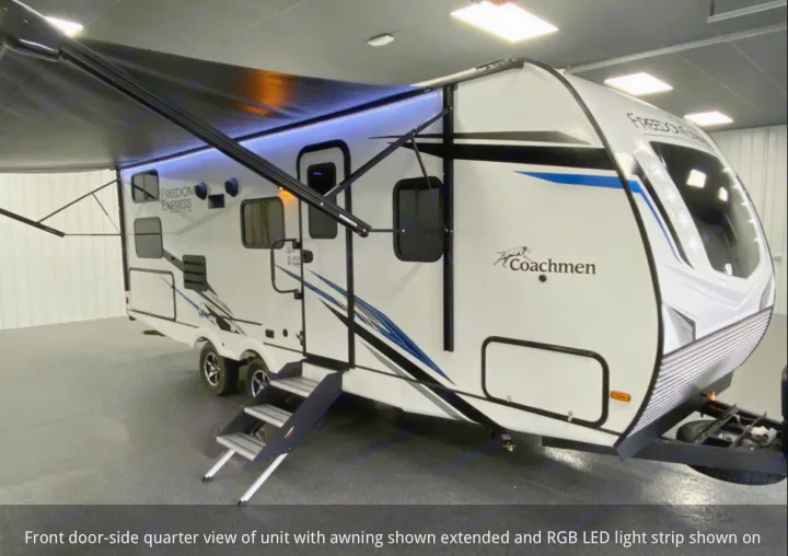 White Coachmen Freedom Express RV, ideal for rv rental, features an extended awning with blue LED lighting and steps.. Coachmen 257BHS 2022