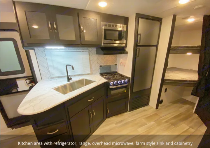 Spacious RV rental kitchen: fridge, stove, microwave, stainless sink, dark cabinetry & bunk beds.. Coachmen 257BHS 2022