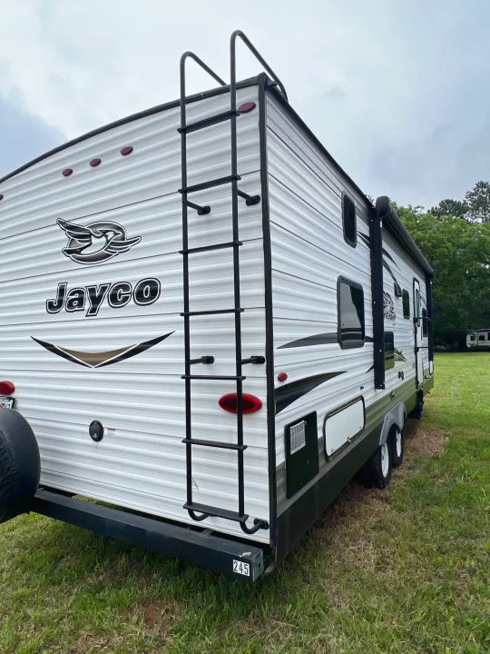 Rear view of a white Jayco travel trailer with a ladder, parked on grass. Great for an RV rental experience.. Jayco Jay Flight 2018