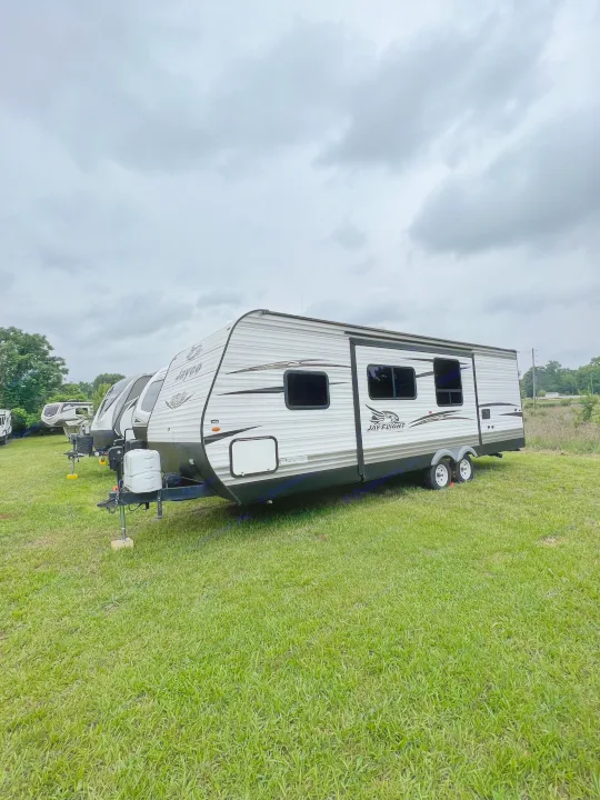 A line of new Jayco Jay Flight travel trailers on green grass under a cloudy sky, ideal for your next RV rental adventure.. Jayco Jay Flight 2018