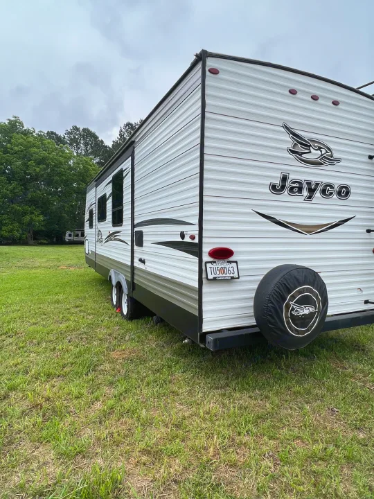 White Jayco RV rental parked on a grassy field under a cloudy sky, ready for outdoor adventures.. Jayco Jay Flight 2018