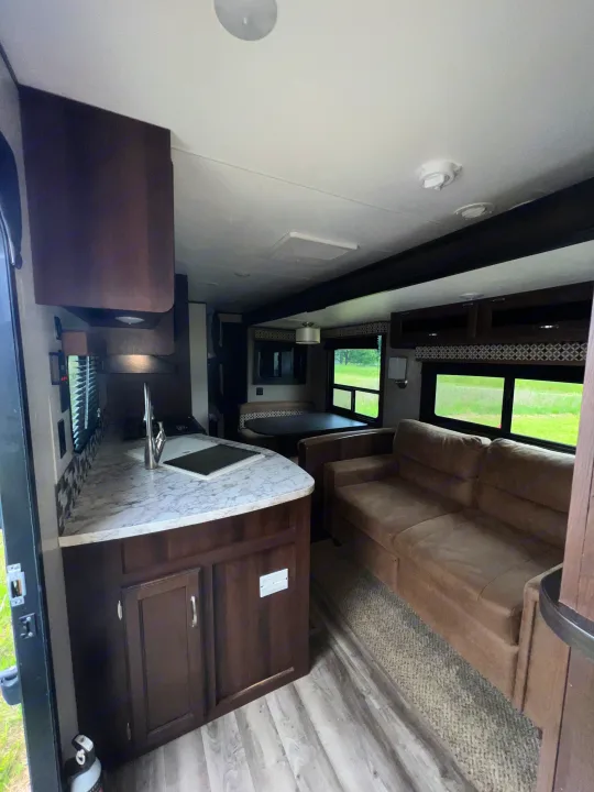 Explore this bright RV rental interior featuring a modern kitchen, comfy sofa, and dinette, ideal for a relaxing journey.. Jayco Jay Flight 2018