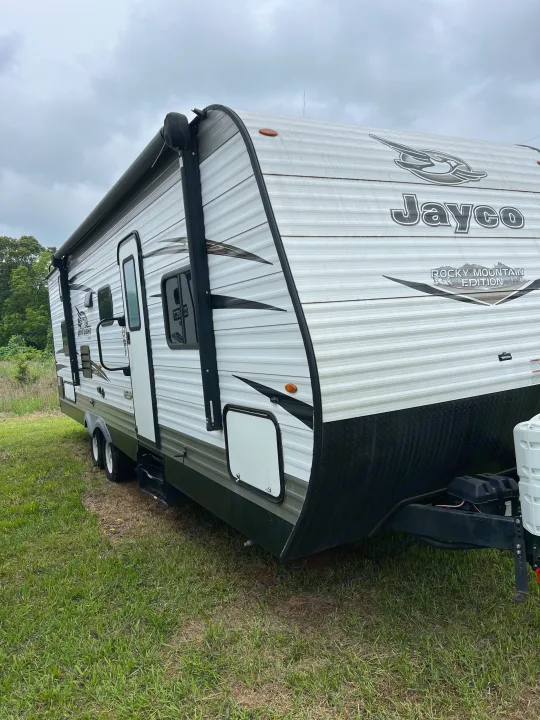 This white Jayco Jay Flight travel trailer, seen parked on grass, offers an excellent RV rental option for your outdoor adventures.. Jayco Jay Flight 2018