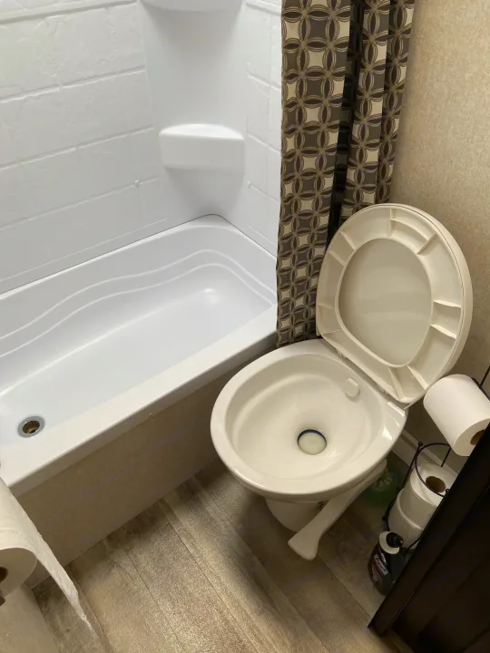 Clean RV rental bathroom with white tub, shower, patterned curtain, and toilet. Compact design.. Jayco Jay Flight SLX 2018