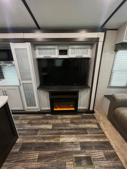 Modern RV rental entertainment area with TV, electric fireplace, and sleek cabinetry.. Keystone RV Bullet Premier Ultra 2020