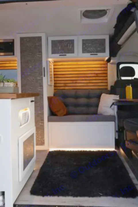 Modern camper van interior for RV rental. Features a cozy bench seat with wood slat walls & warm lighting, inviting comfort.. Dodge B Van 2020