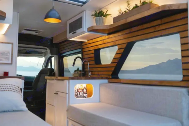 Cozy RV rental interior with a functional kitchen, living area, and stunning lake and mountain views through the windows.. Dodge B Van 2020