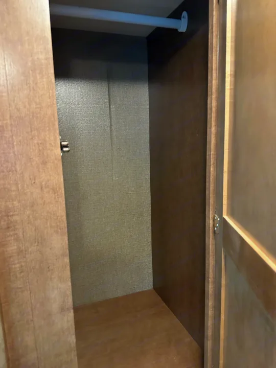 Empty RV rental wardrobe: a compact, wood-toned closet with a white hanging rod, ready for storage.. Winnebago Outlook 2019