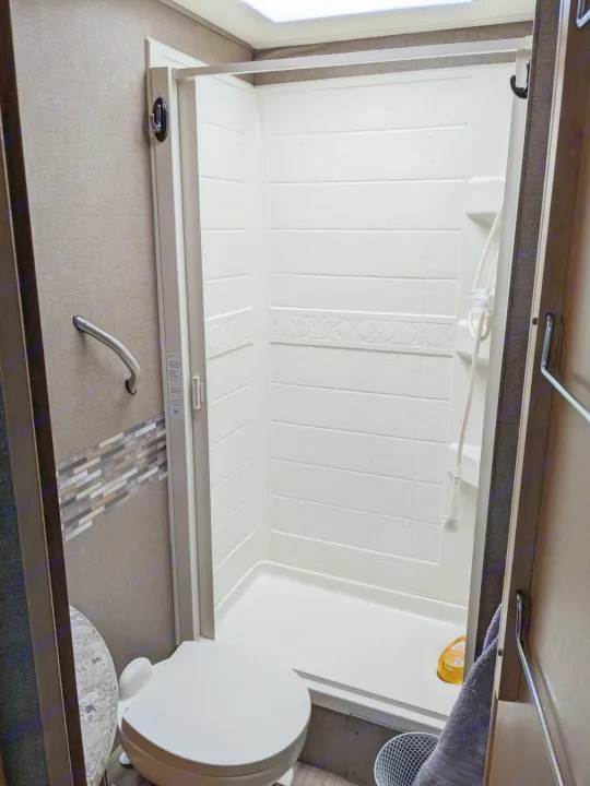 RV rental interior: Compact bathroom featuring a shower stall, toilet, and a wall-mounted grab bar.. Thor Freedom Elite 2017
