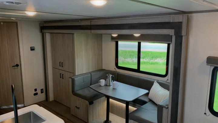 Inside a modern **rv rental**: A comfortable dinette with a table, ample storage cabinets, and a partial kitchen view.. Keystone RV Passport SL 2022