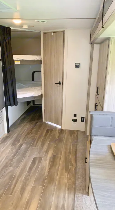 RV rental interior: bright, modern space with wood-look flooring, cozy bunk beds, and a dinette.. Keystone RV Passport SL 2022