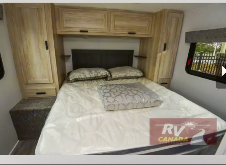 Cozy RV rental bedroom with a comfortable bed, light wood cabinets, and a window. Ideal for travelers.. Forest River Sunseeker LE 2023