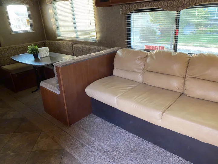 This RV rental interior offers a comfortable dinette with patterned benches and a large beige couch, ready for your adventures.. Heartland RVs 30LX 2014