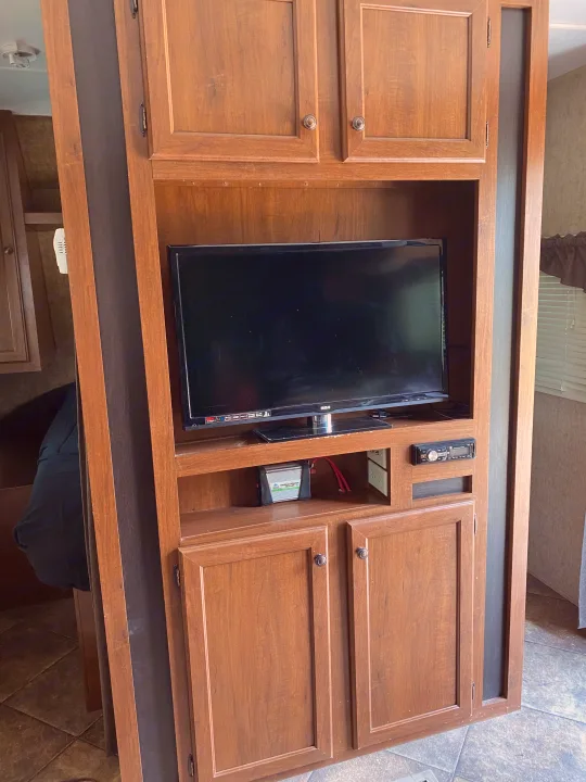 This RV rental features a wooden entertainment center with an RCA TV, stereo system, and mobile power inverter.. Heartland RVs 30LX 2014