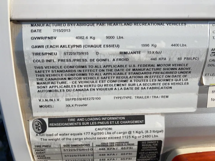 Close-up of an RV rental trailer's spec label, with GVWR, tire pressure, and cargo weight details.. Heartland RVs 30LX 2014
