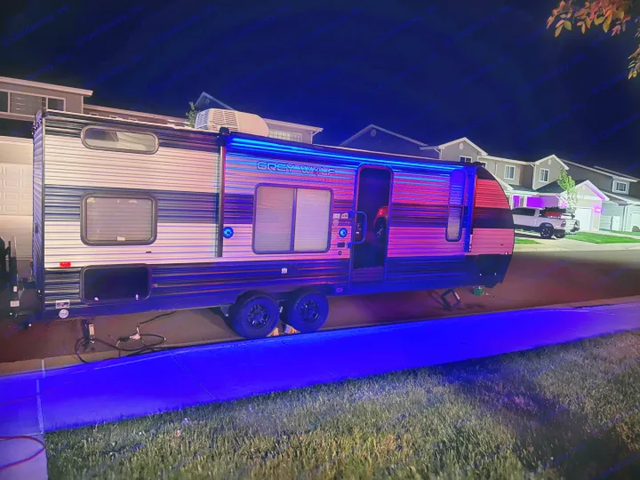 An RV rental, a Grey Wolf travel trailer, glowing with bright blue LED lights at night on a street.. Forest River Cherokee Grey Wolf Special Edition 2022