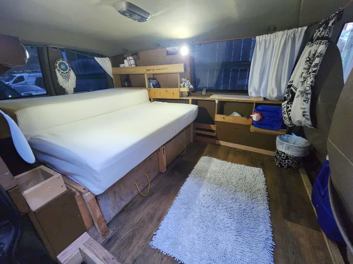 Cozy RV rental interior showcasing a comfortable bed, smart built-in storage, and warm lighting for mobile adventures.. Chevrolet Open Road 2000