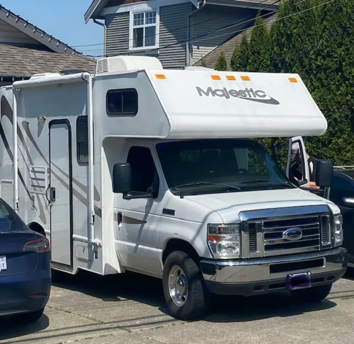 Bright white Majestic RV rental, a Ford Class C motorhome, parked on pavement. Perfect for camping trips.. Thor Majestic 2016