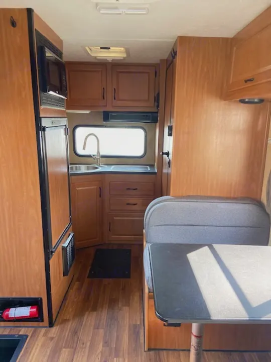 This RV rental shows its compact interior, including a kitchen, dining area, and wood cabinets.. Thor Majestic 2016