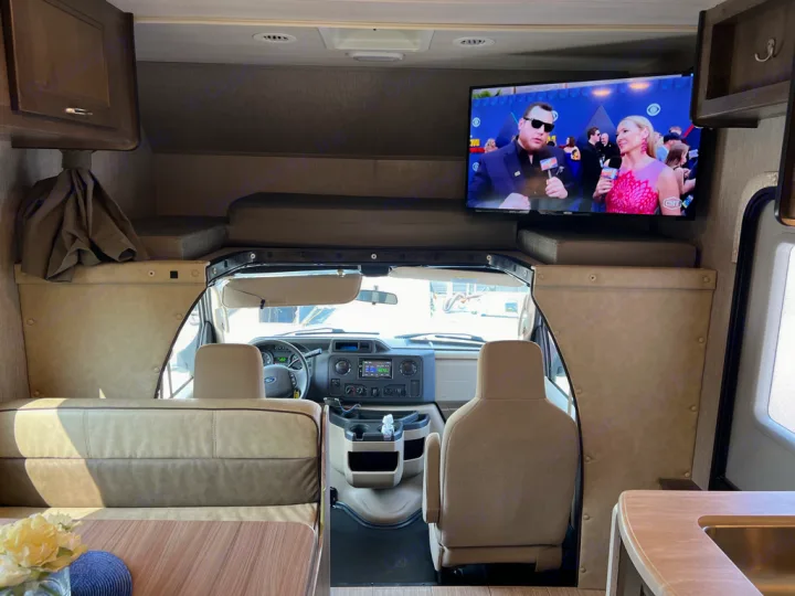 Spacious RV rental interior featuring an overhead bunk, TV, and front cockpit. Ready for adventure!. Nexus Triumph 23T 2020