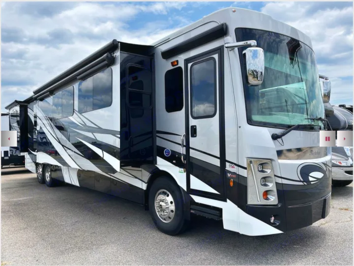A sleek white and black luxury Class A motorhome, with its slide-outs extended, ready for your next rv rental trip.. Berkshire XLT 2023