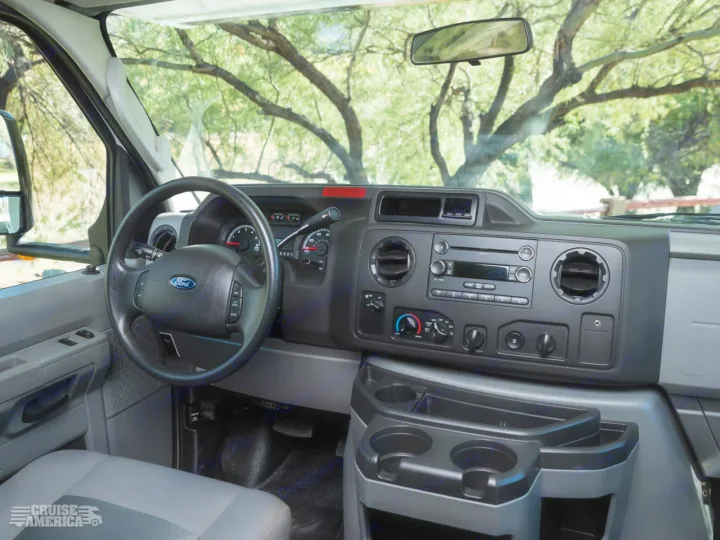 RV rental interior: Driver's view with steering wheel, dashboard controls, and cup holders. Ready for adventure!. Thor Majestic 2016