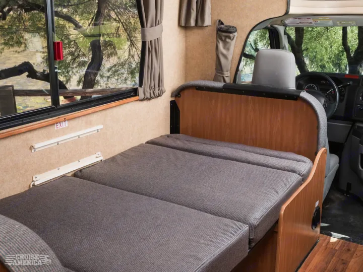 RV rental interior showcases a convertible bed/dinette setup, large window with outdoor views, and emergency exit.. Thor Majestic 2016