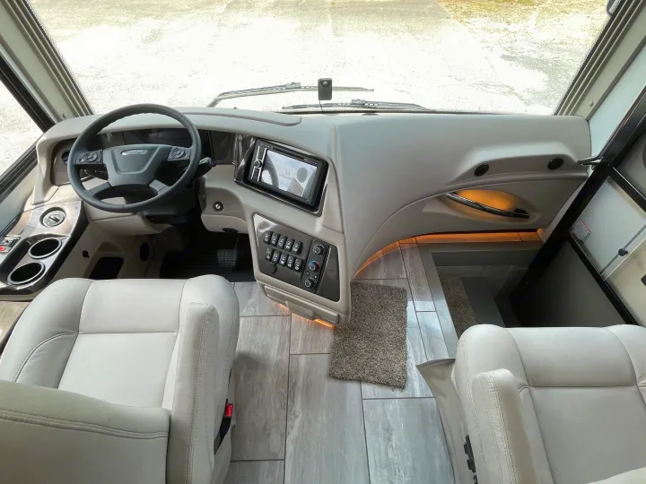 View inside an RV rental cockpit, showing the driver's area with steering wheel, modern dashboard, and light-colored seats.. Berkshire XLT 2023