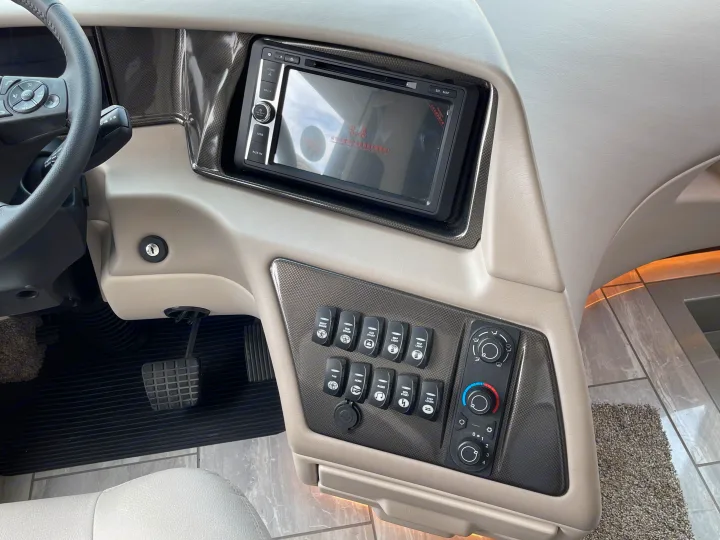 Detailed view of an RV rental driver's dashboard, showing a multimedia screen, climate controls, and various vehicle function buttons.. Berkshire XLT 2023