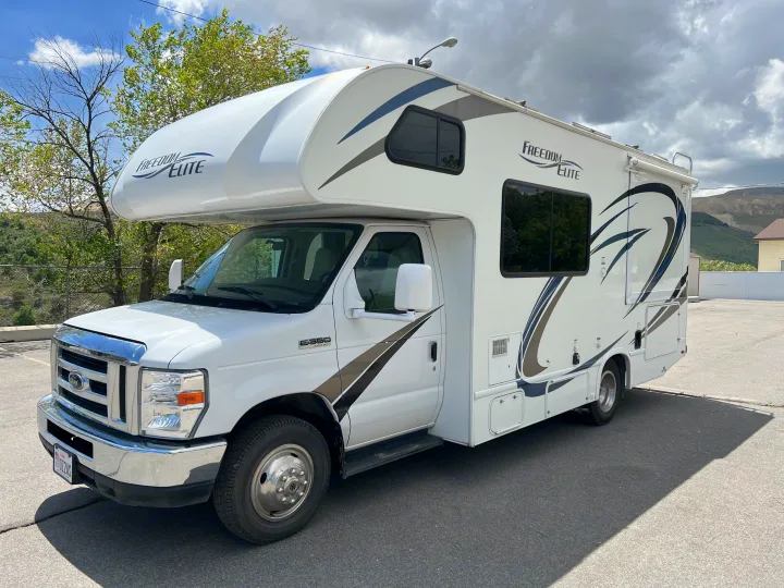 Spacious white Freedom Elite rv rental, a Class C motorhome on a Ford E-350 chassis, parked under cloudy sky.. Thor Motor Coach Freedom Elite 2018