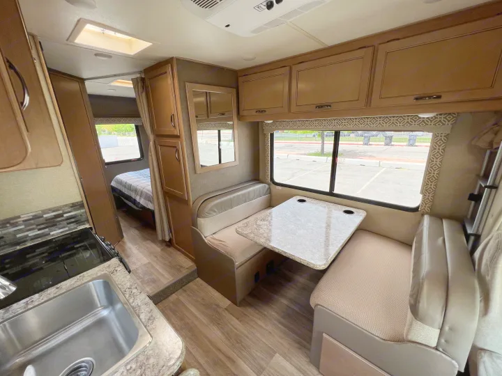 This RV rental offers a well-equipped kitchen, comfortable dining booth, and rear bedroom, perfect for your next trip.. Thor Motor Coach Freedom Elite 2018