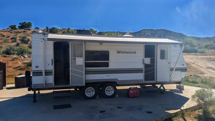 Wildwood travel trailer parked on concrete with awning extended, ready for an RV rental adventure under clear desert skies.. Forest River Wildwood 2005