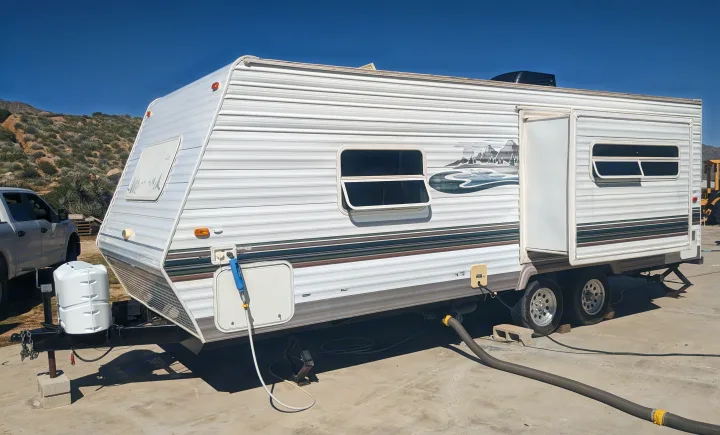 White rv rental travel trailer, fully set up with utility hookups on concrete, ideal for outdoor trips.. Forest River Wildwood 2005
