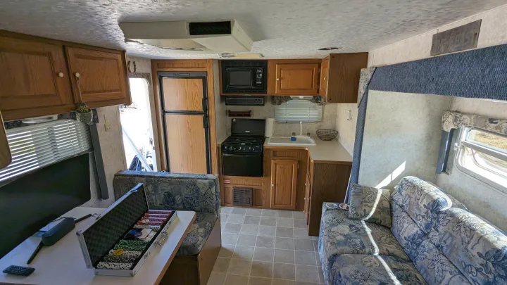 RV rental interior: full kitchen with microwave, fridge, stove, a dining booth with poker chips, and a comfy sofa.. Forest River Wildwood 2005