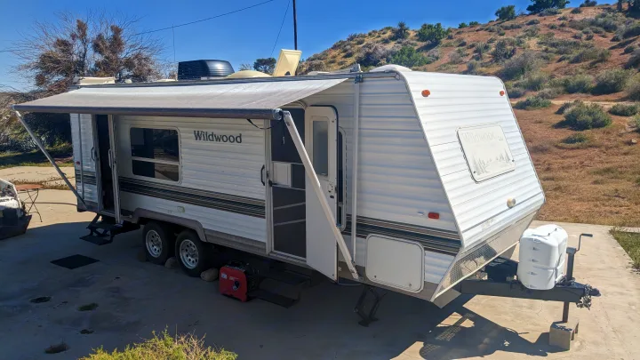Experience outdoor living! This Wildwood travel trailer is ready for your next rv rental, parked in a sunny desert landscape.. Forest River Wildwood 2005