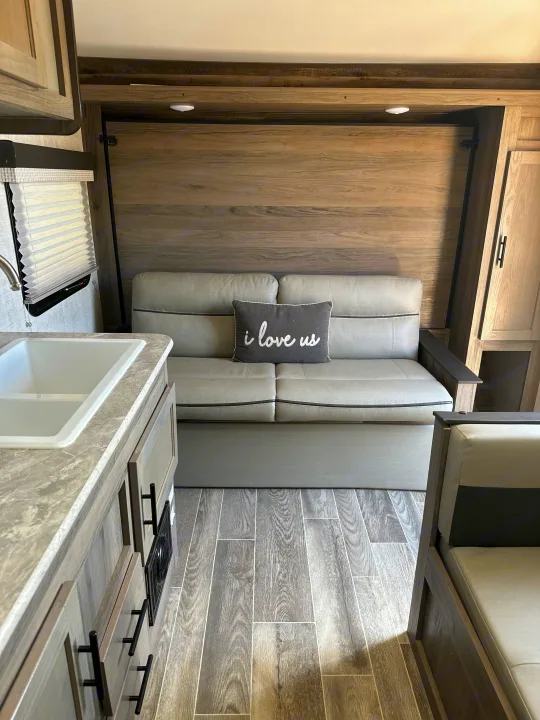 Explore this RV rental's inviting interior: modern kitchen, comfortable sofa with "i love us" pillow, and dinette.. Gulf Stream Ameri-Lite Super Lite 2022