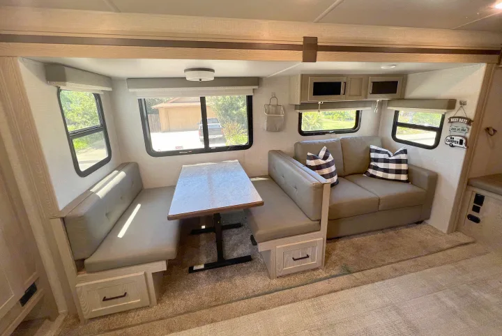 Comfortable RV rental interior featuring a spacious dinette, sofa, ample storage, and bright windows for your travels.. Forest River Rockwood Roo 235S